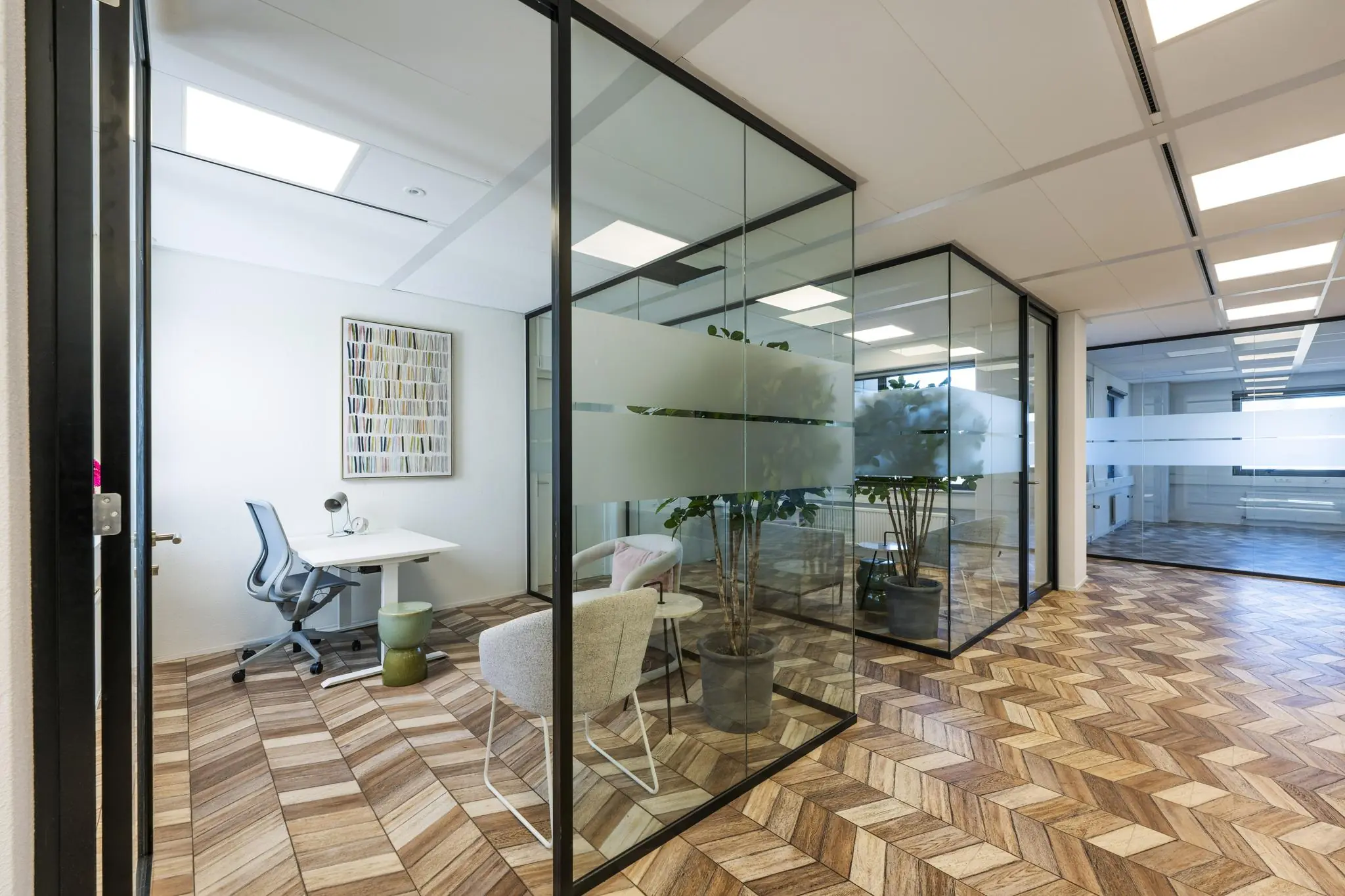 Modern kantoorinterieur aan de Overschiestraat met glazen wanden, houten visgraatvloer en stijlvolle werkplekken.