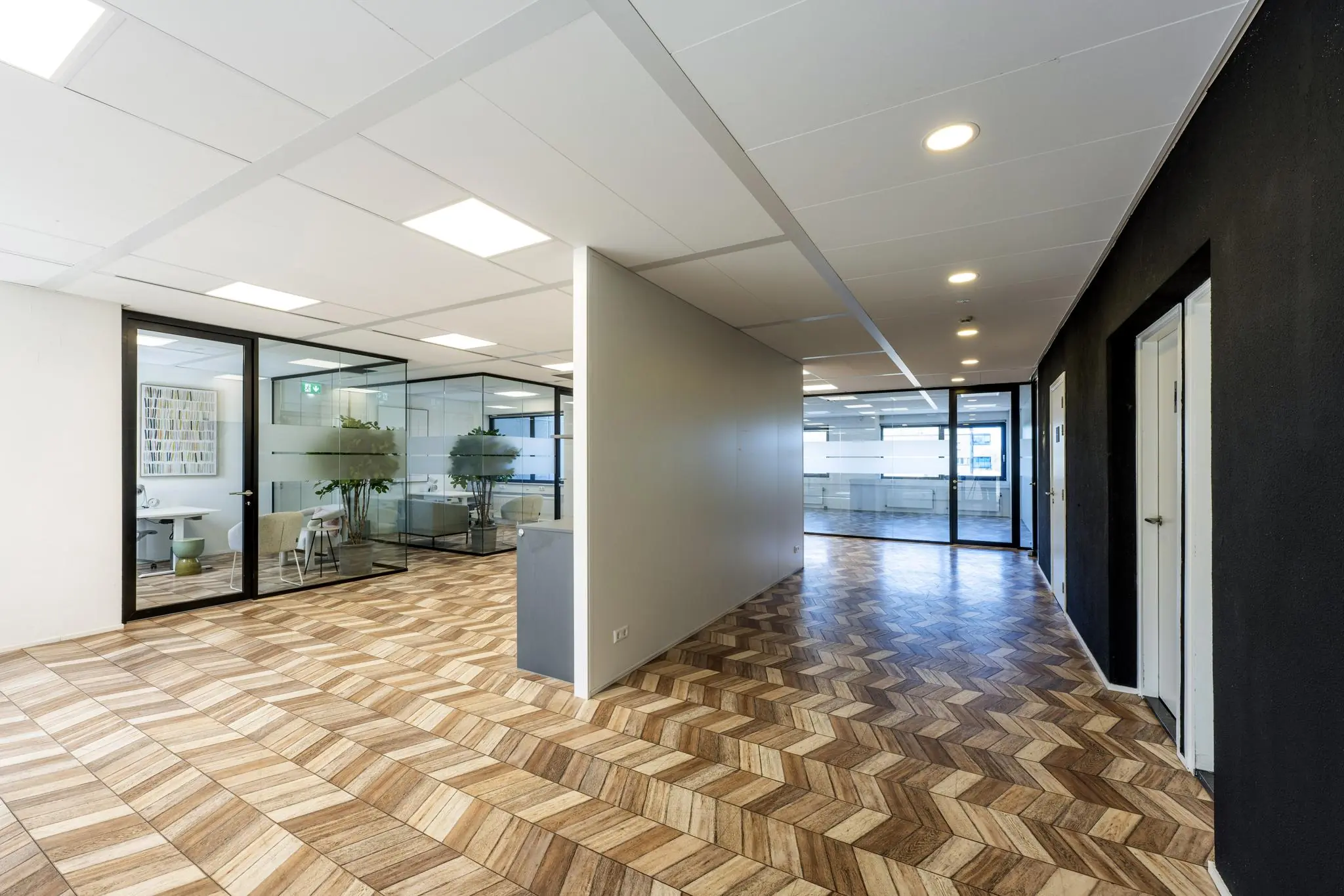 Moderne kantoorruimte aan de Overschiestraat met glazen vergaderruimtes en houten visgraatvloer.