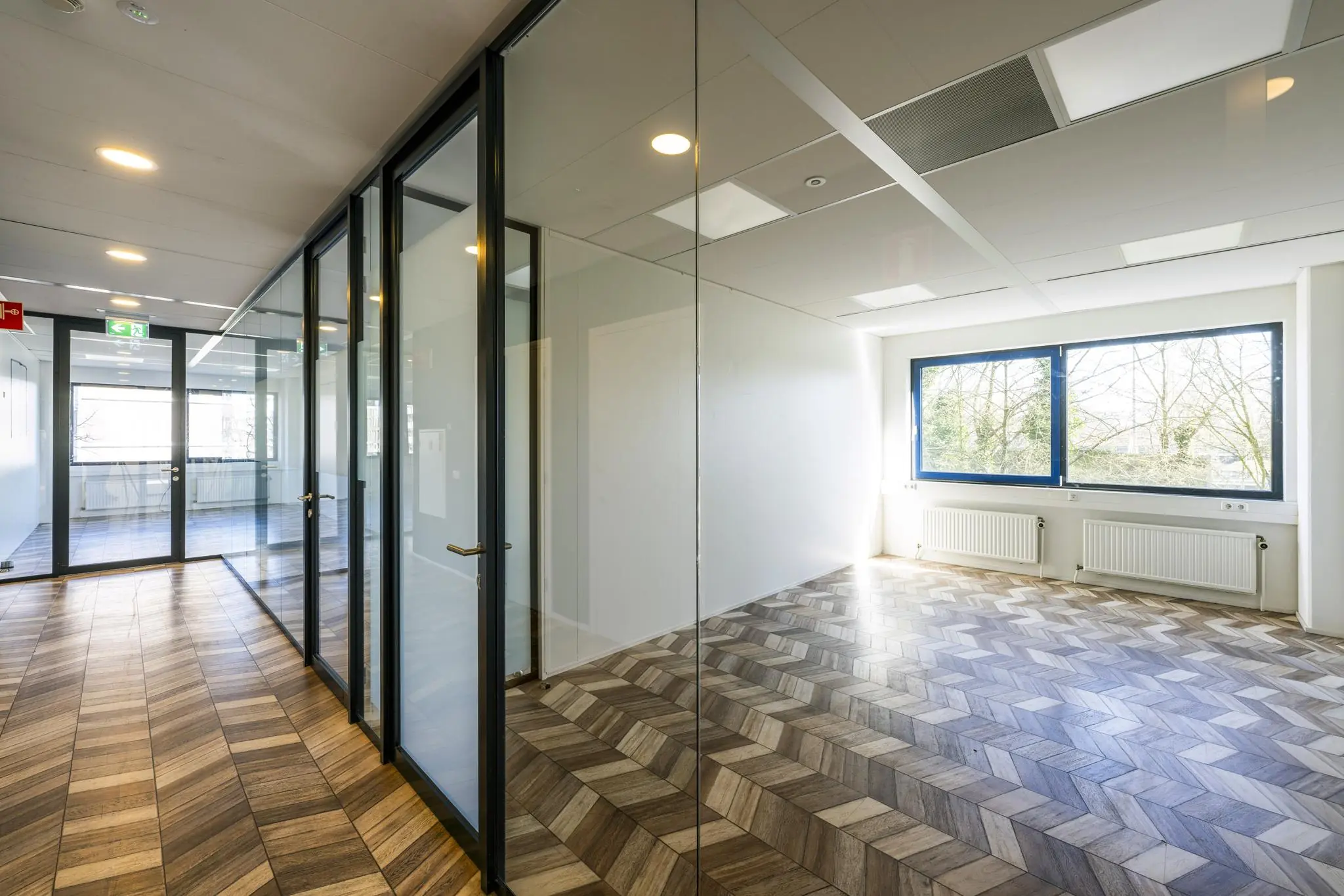 Licht en modern kantoorinterieur aan de Overschiestraat met glazen wanden en visgraatvloer.