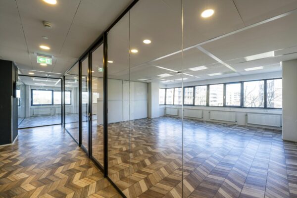 Moderne, lege kantoorruimte aan de Overschiestraat met glazen wanden en visgraatvloer.