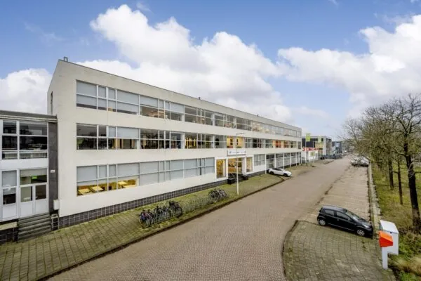 Kantoorgebouw aan de Van der Madeweg met fietsenrekken en geparkeerde auto's langs een rustige straat.