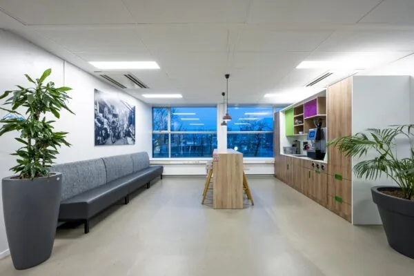 Moderne bedrijfskantine met zithoek, hoge tafel, koffiehoek en grote ramen aan de Van der Madeweg.