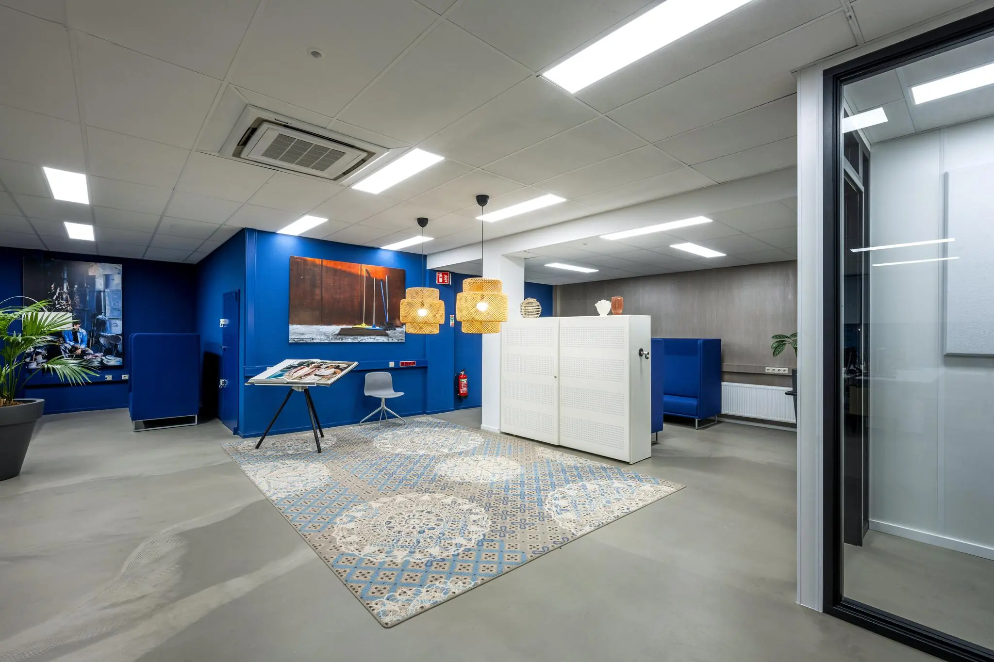 Modern ingerichte kantoorruimte aan de Van der Madeweg met blauwe accenten, kunst aan de muur en een decoratief vloerkleed.