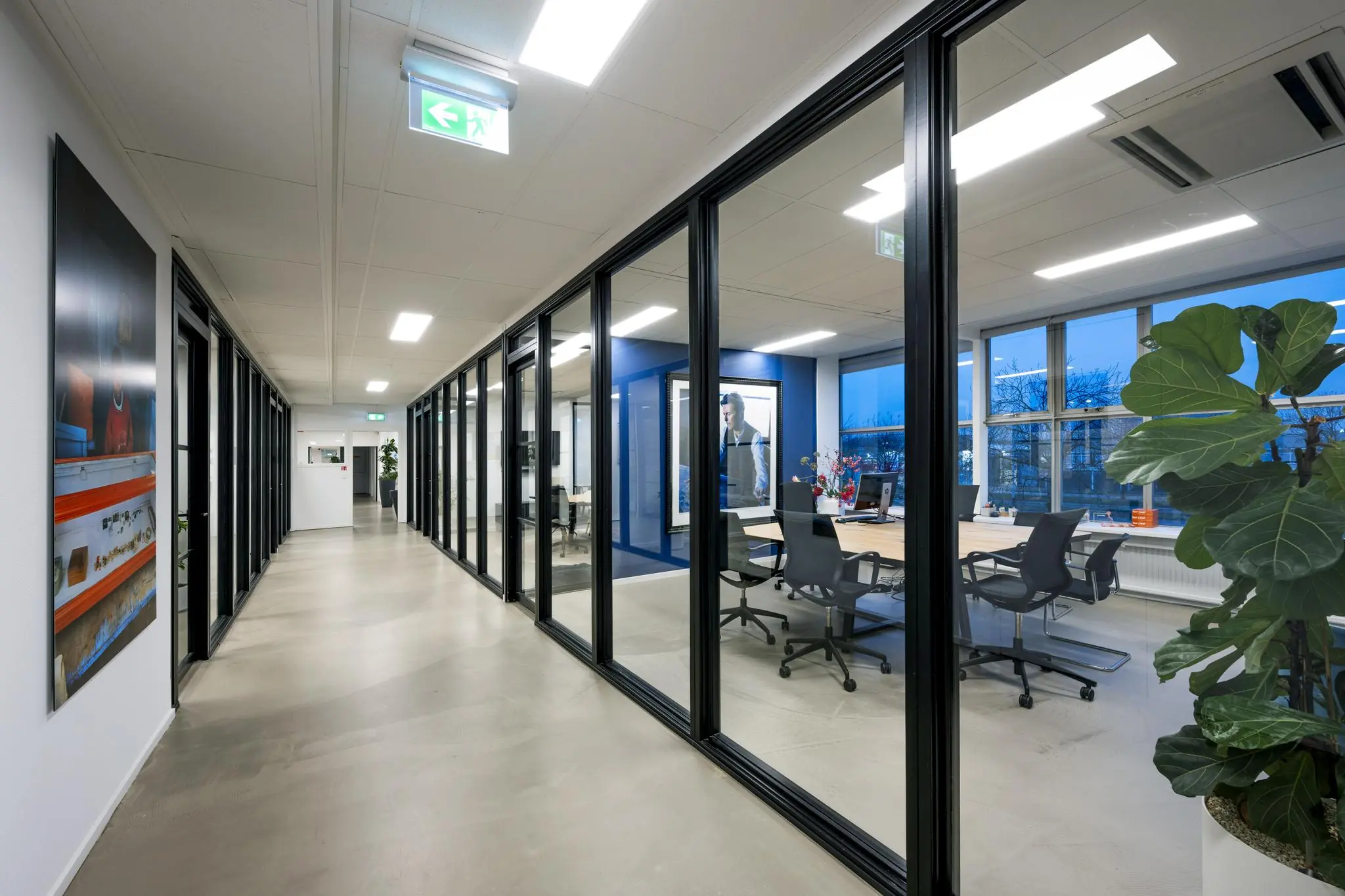 Moderne kantoorruimte aan de Van der Madeweg met glazen vergaderruimtes en een strakke, lichte gang.