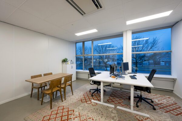 Modern ingericht kantoor aan de Van der Madeweg met werkplekken, vergadertafel en uitzicht op de straat.
