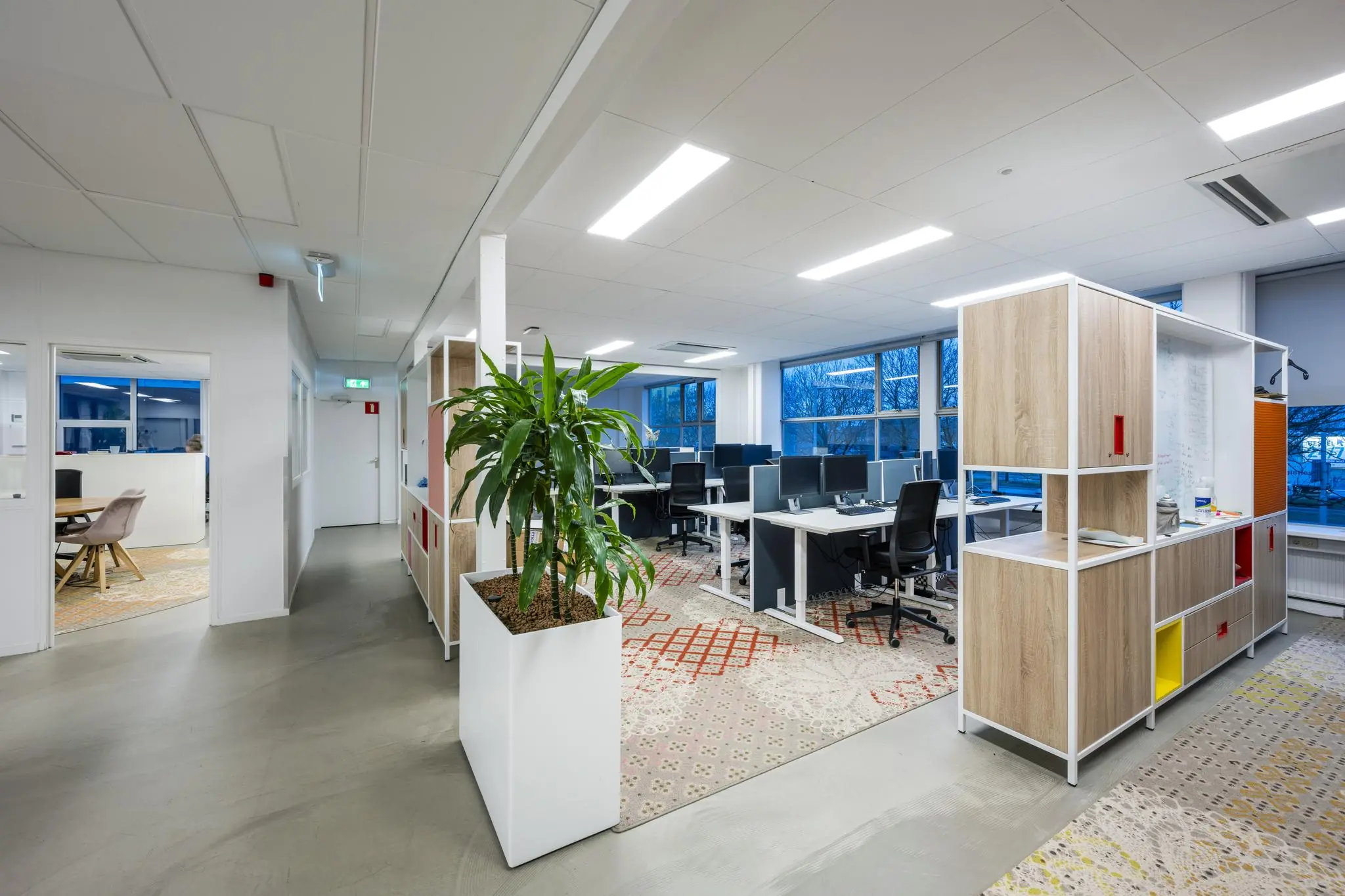 Moderne kantoorruimte aan de Van der Madeweg met open werkplekken, grote ramen en kleurrijke inrichting.