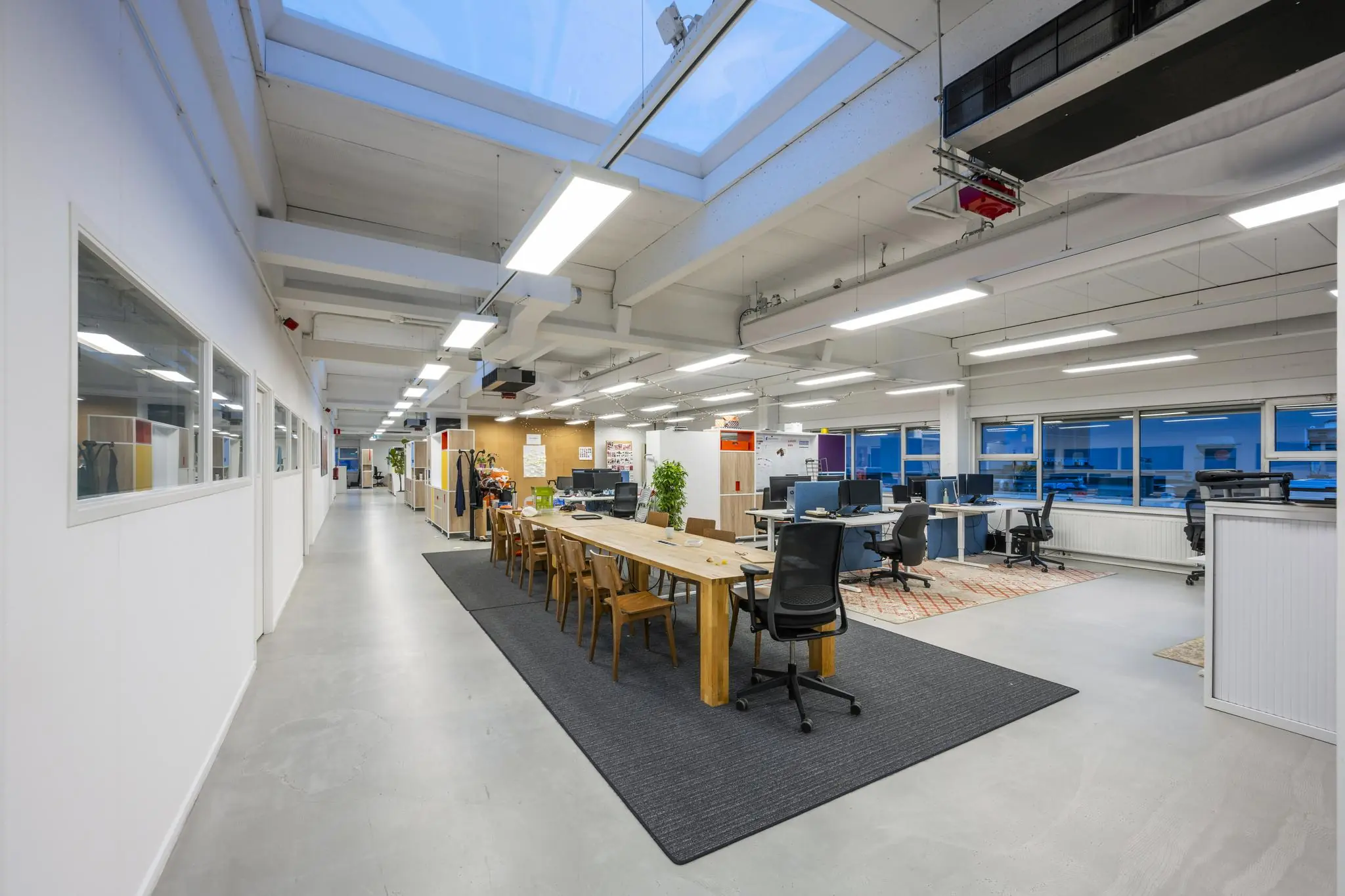 Moderne, open kantoorruimte aan de Van der Madeweg met bureaus, vergadertafel en grote ramen.