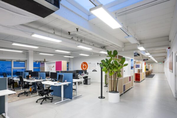 Modern en licht kantoorinterieur aan de Van der Madeweg met werkplekken, planten en open vergaderruimte.