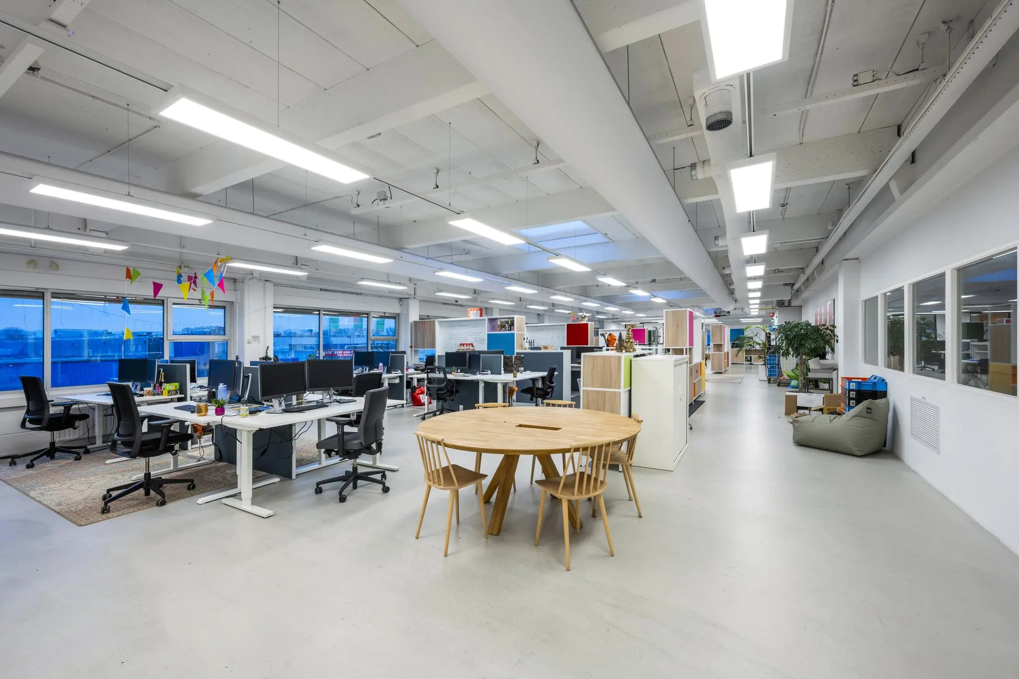 Moderne open kantoorruimte aan de Van der Madeweg met bureaus, computers, vergadertafel en kleurrijke decoratie.