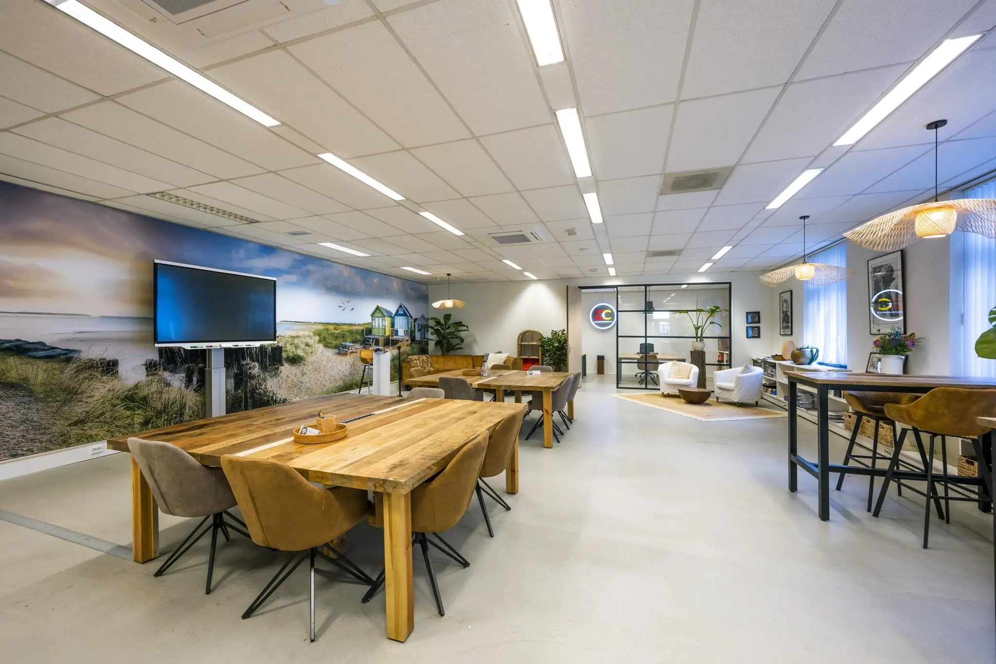 Moderne en sfeervolle kantoorruimte aan de Helicopterstraat met houten meubilair, strandfotobehang en diverse zithoeken.