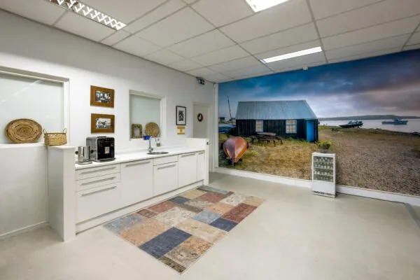 Moderne pantry met witte keuken en fotowand van een vissershut aan het water in Helicopterstraat.