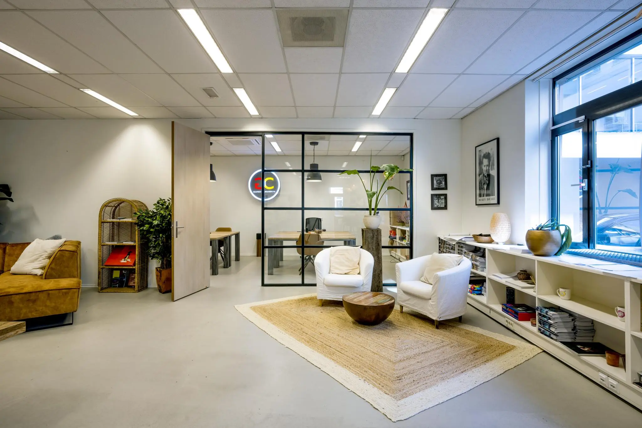 Moderne kantoorruimte aan de Helicopterstraat met een zithoek, glazen vergaderruimte en natuurlijke decoratie.