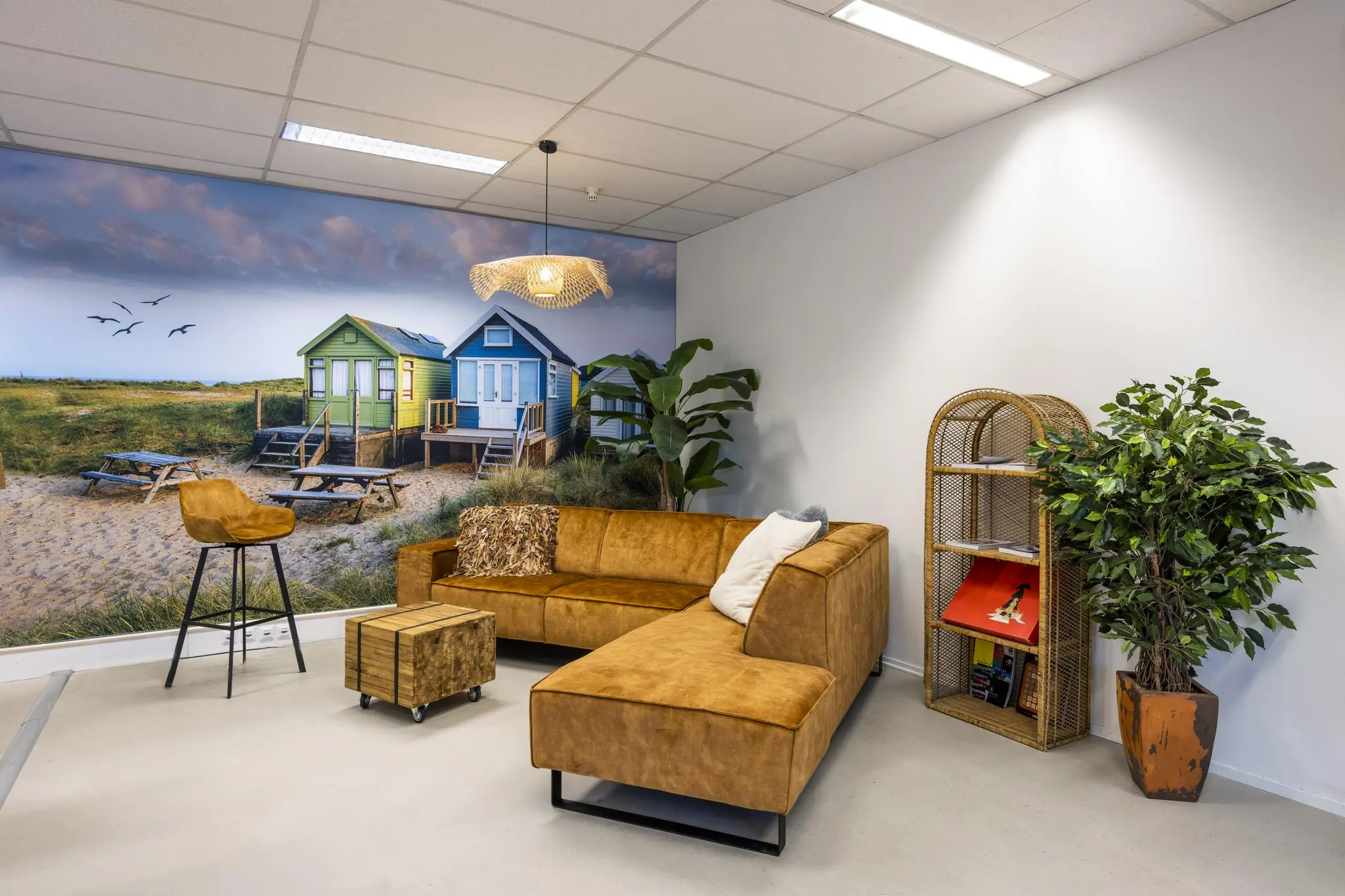 Modern ingerichte loungehoek met bruine bank en strandhuisjes-muurschildering in een kantoor aan de Helicopterstraat.
