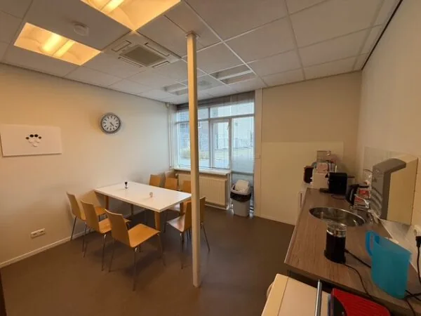 Kleine, eenvoudige kantine met een tafel, zes stoelen, keukenblok en koffieapparaten aan de Fonteynenburghlaan.