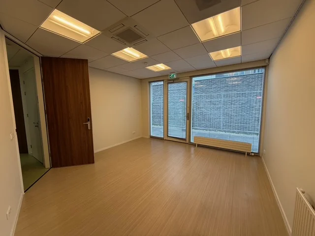 Leeg kantoorruimte met houten vloer, systeemplafond en glazen deur aan de Fonteynenburghlaan.
