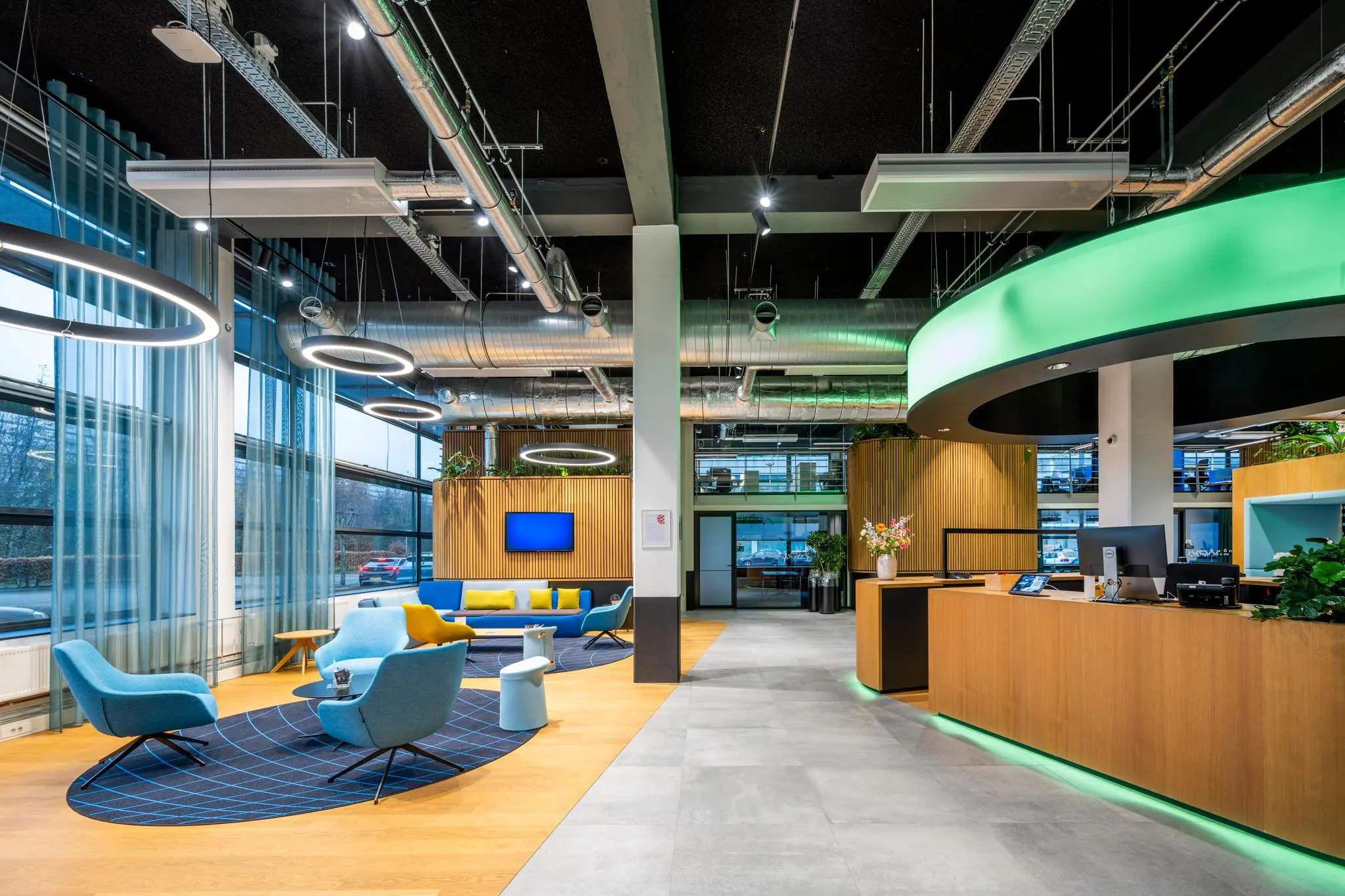 Moderne kantoorlobby aan de Kabelweg met wachtruimte, receptiebalie en opvallende verlichting.
