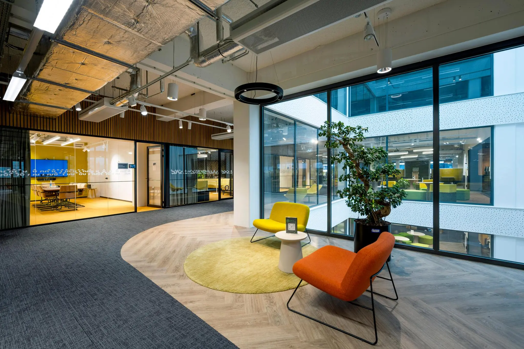 Moderne kantoorlobby aan de Kabelweg met kleurrijke zitstoelen, grote ramen en uitzicht op aangrenzende werkruimtes.