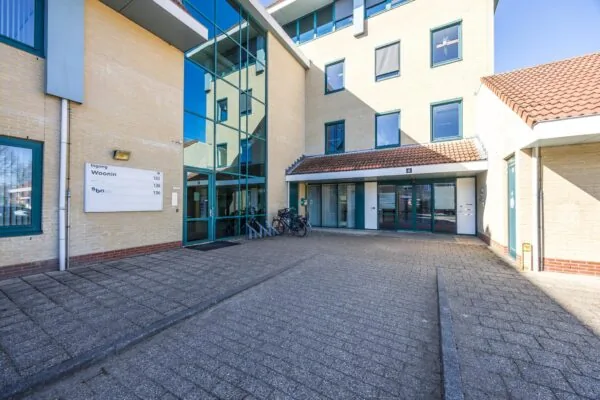 Ingang van een modern woon- en kantoorgebouw aan de Dorpsstraat met fietsenstalling en blauwe kozijnen.