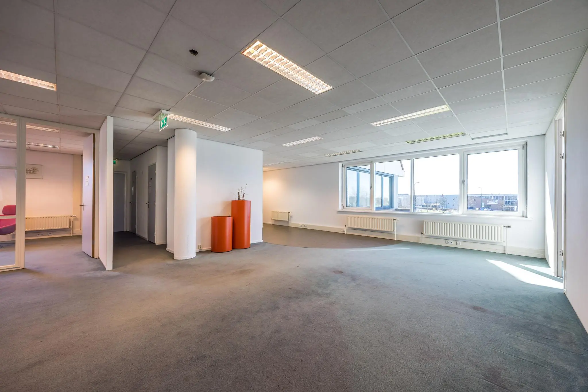 Lichte, deels gemeubileerde kantoorruimte aan de Dorpsstraat met grote ramen en kunstverlichting.