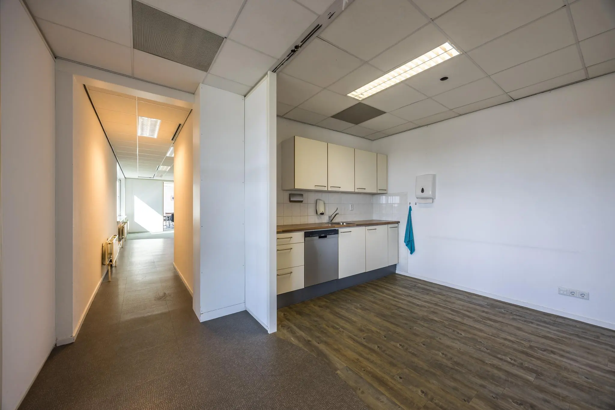 Keukenblok in een kantoorruimte met aangrenzende gang en zicht op vergaderruimte aan de Dorpsstraat.