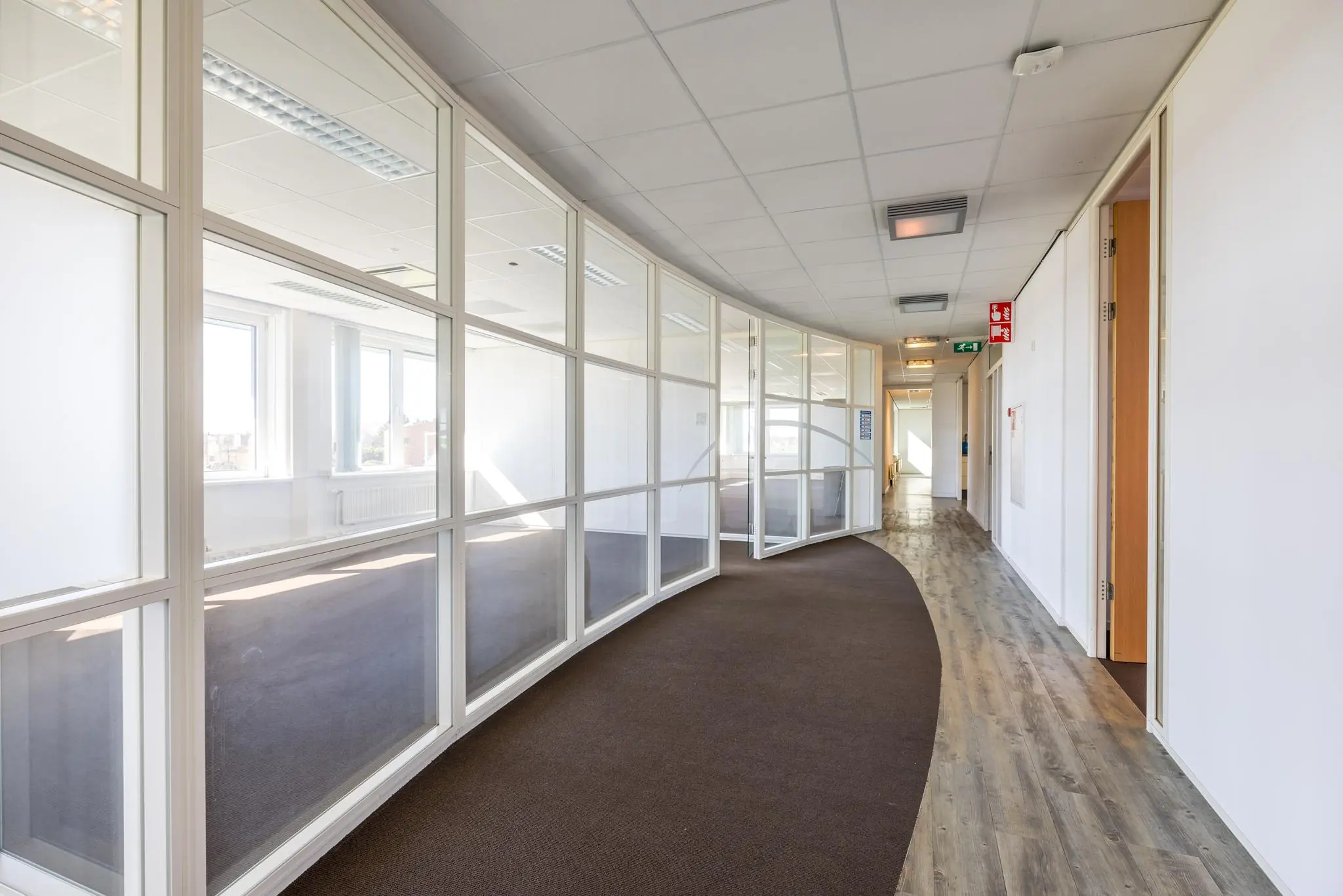 Lichte en moderne kantoorruimte aan de Dorpsstraat met glazen tussenwanden en een gebogen gangpad.