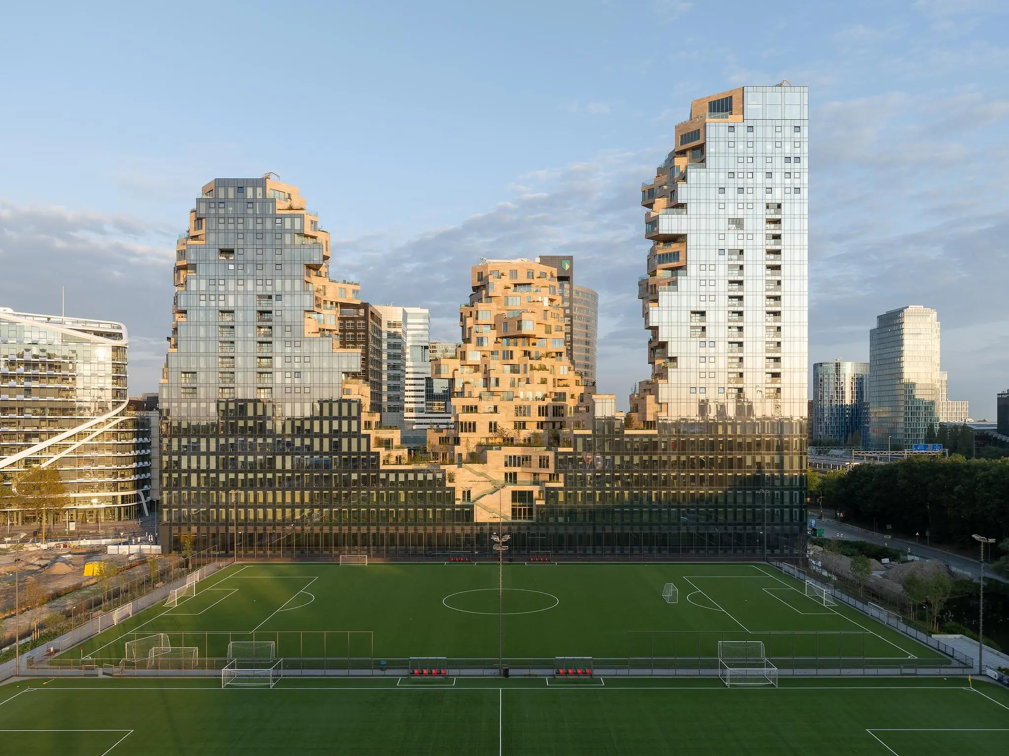 Modern wooncomplex aan de Beethovenstraat in Amsterdam, met opvallende trapsgewijze architectuur en een voetbalveld op de voorgrond.