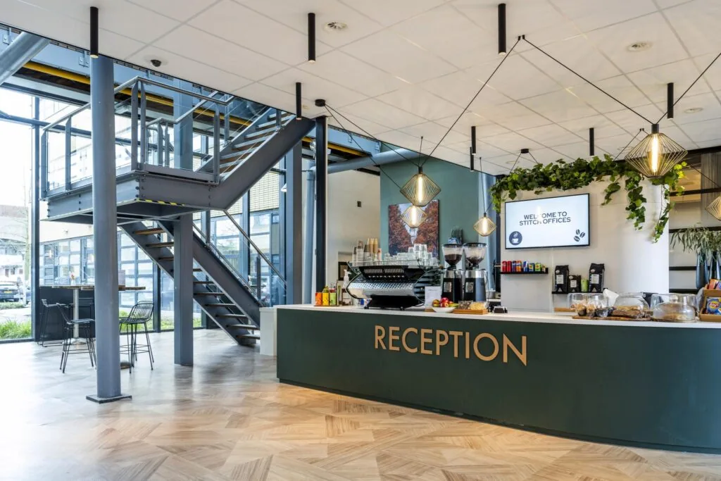 Moderne receptiebalie met koffiebar in de entree van Stitch Offices aan de H.J.E. Wenckebachweg.