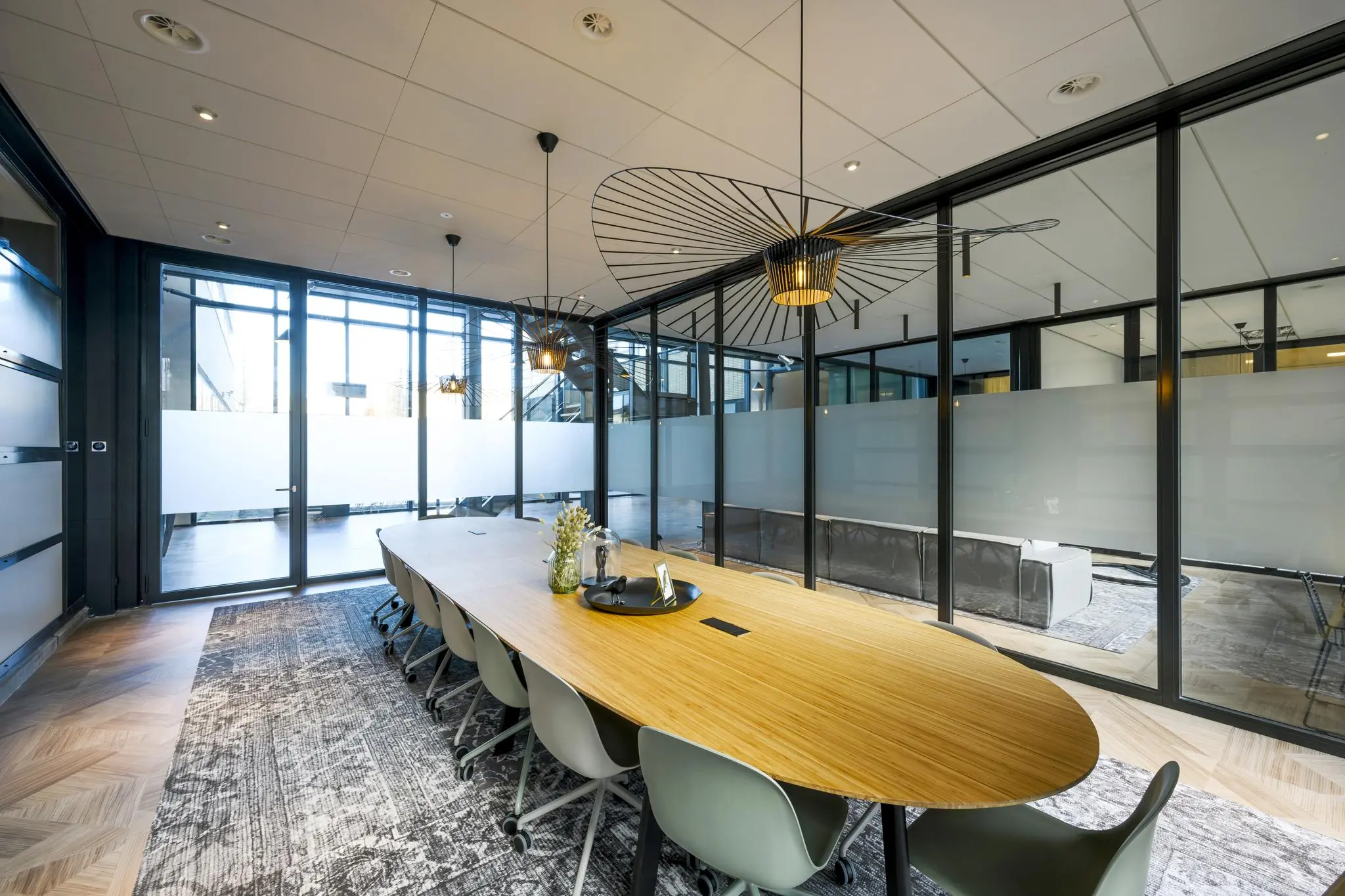 Moderne vergaderruimte aan de H.J.E. Wenckebachweg met een lange houten tafel, designverlichting en glazen wanden.
