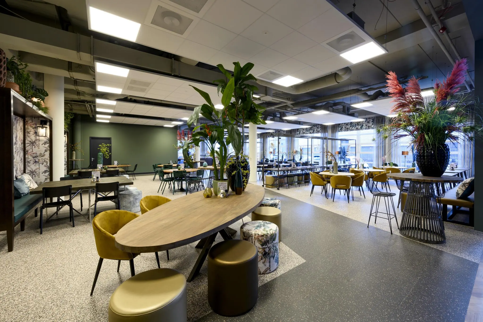 Moderne en sfeervol ingerichte kantine aan de H.J.E. Wenckebachweg met diverse zitplekken, planten en grote ramen.
