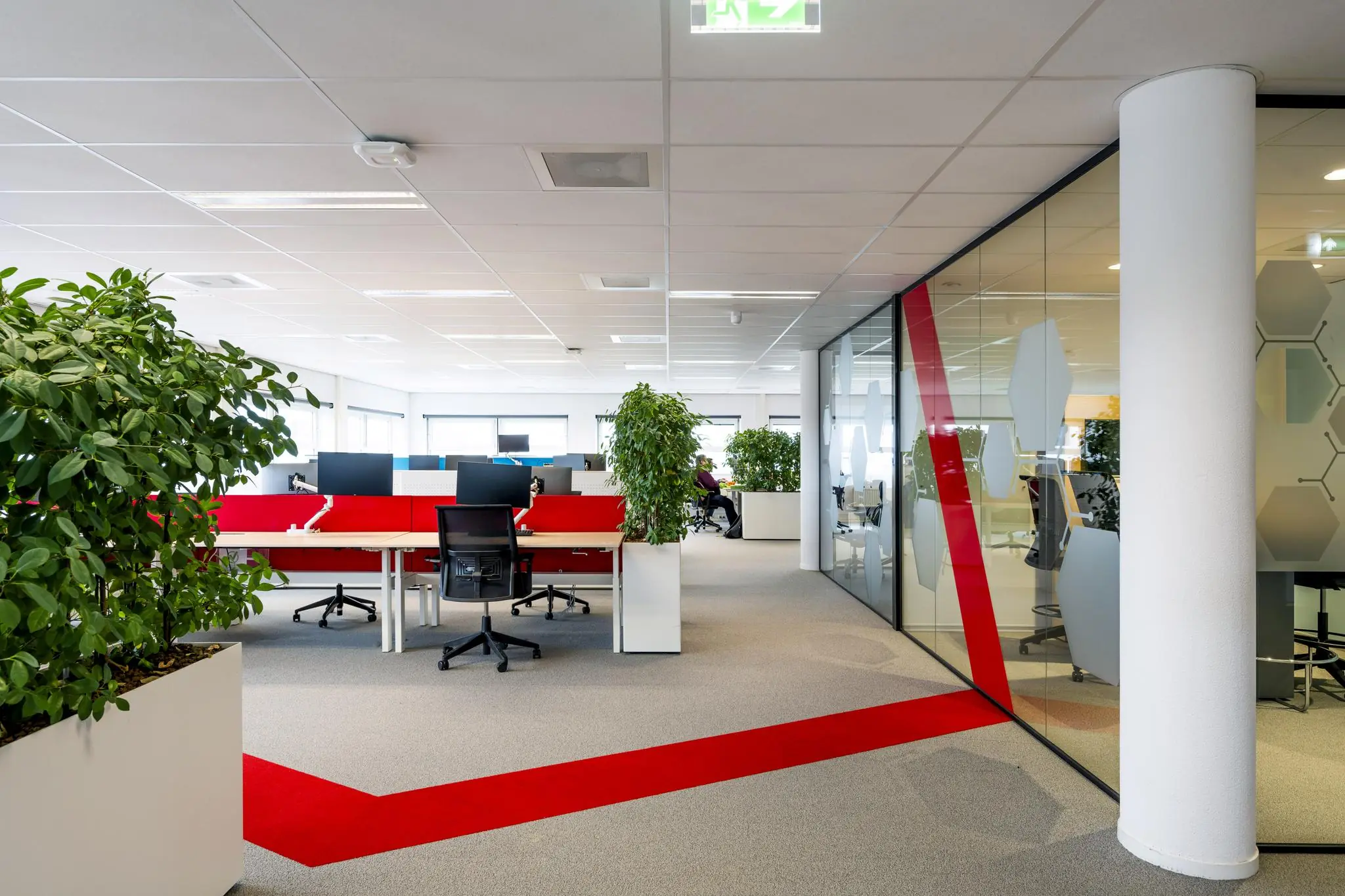 Moderne kantoorruimte aan de H.J.E. Wenckebachweg met open werkplekken, glazen vergaderruimtes en opvallende rode accenten op de vloer.
