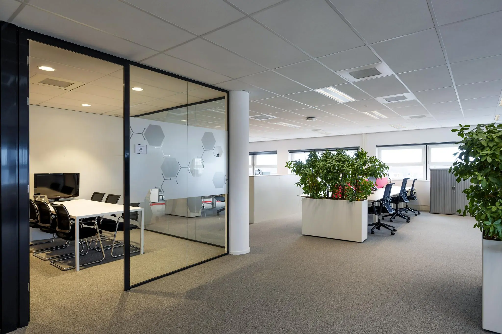 Moderne kantoorruimte aan de H.J.E. Wenckebachweg met een vergaderruimte, werkplekken en groene planten.
