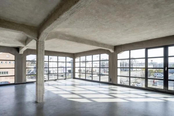 Lichte, industriële ruimte met betonconstructie en grote ramen aan het Gedempt Hamerkanaal.