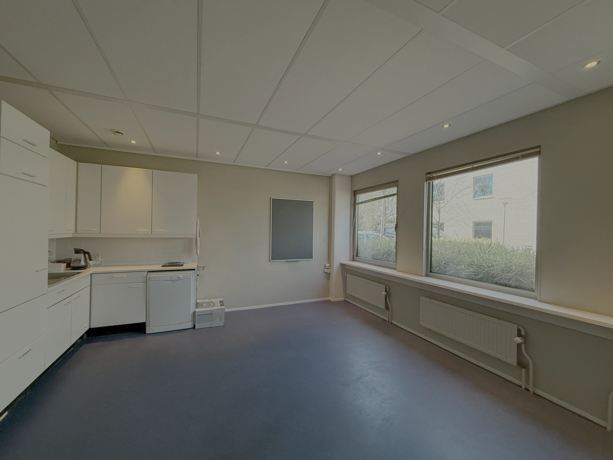 Keukenruimte met witte kasten, een vaatwasser en grote ramen aan de Lunettenbaan.