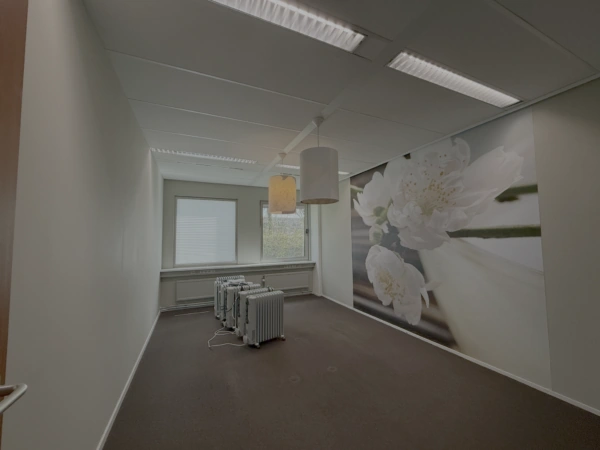 Kleine lege kantoorruimte aan de Lunettenbaan met bloesembehang en meerdere elektrische radiatoren.