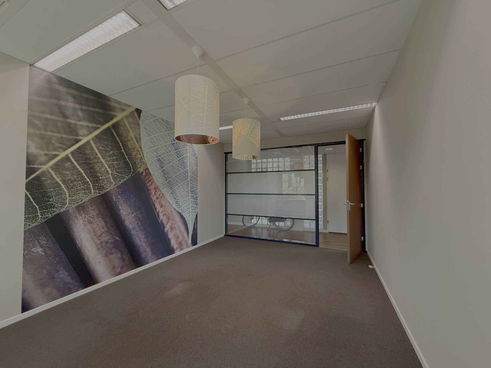 Leeg kantoor aan de Lunettenbaan met een opvallende muurprint van een bladerenmotief en glazen tussenwand.