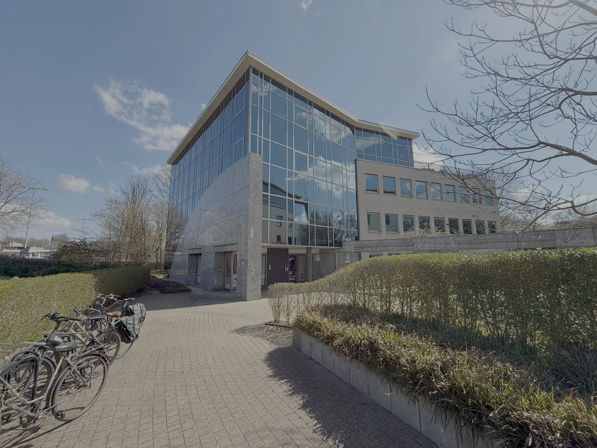 Kantoorgebouw aan de Lunettenbaan met een moderne glazen gevel en fietsenstalling op de voorgrond.
