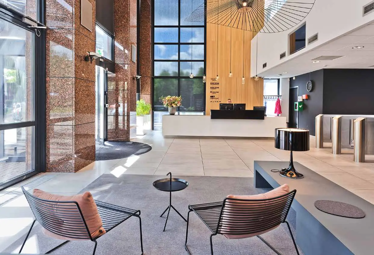 Moderne en lichte ontvangsthal aan de Prof. W.H. Keesomlaan met een receptiebalie, wachtruimte en glazen entree.