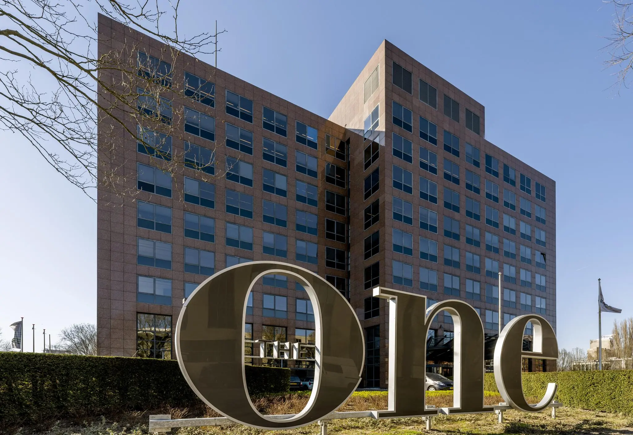 Kantoorgebouw aan de Prof. W.H. Keesomlaan met grote metalen letters "The One" op de voorgrond.