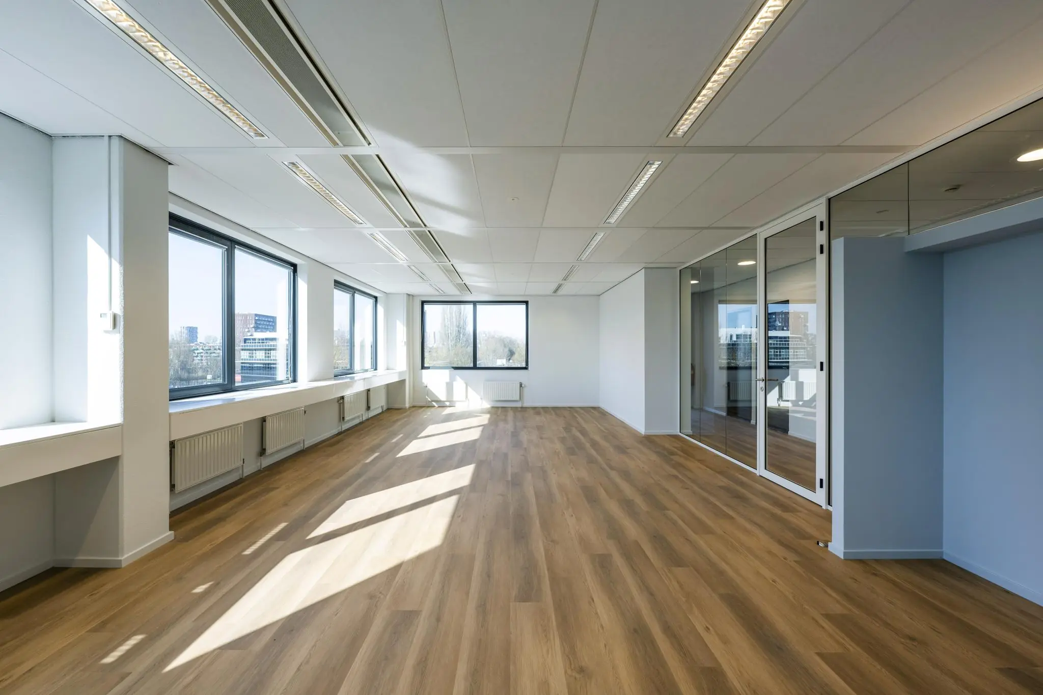 Lichte, moderne kantoorruimte aan de Prof. W.H. Keesomlaan met grote ramen en houten vloer.