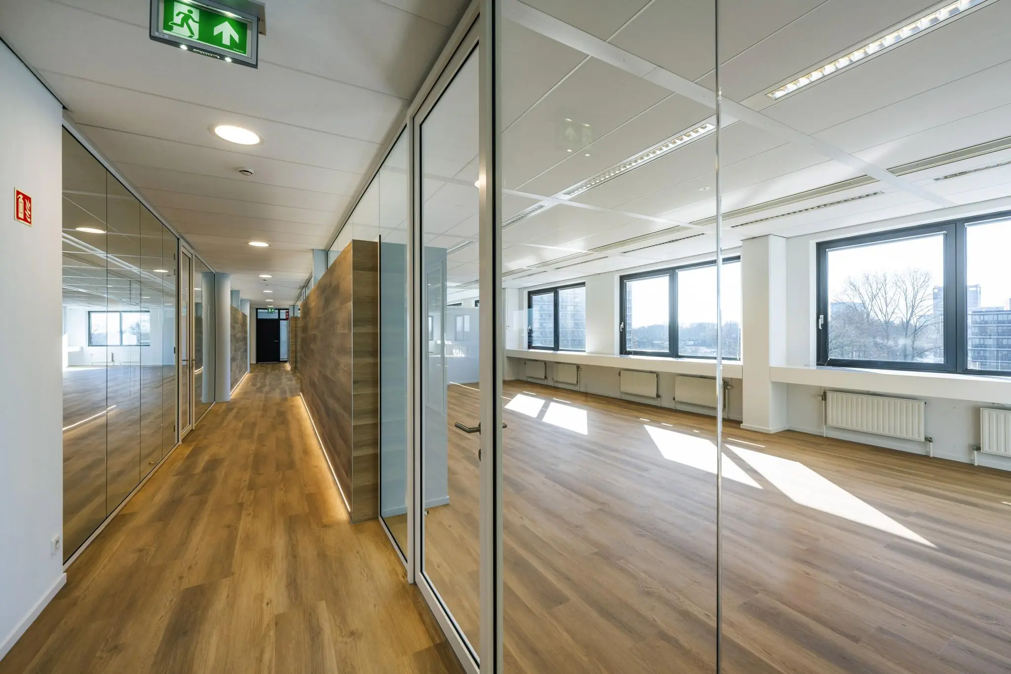 Moderne kantoorruimte aan de Prof. W.H. Keesomlaan met glazen wanden, houten vloer en veel natuurlijk licht.