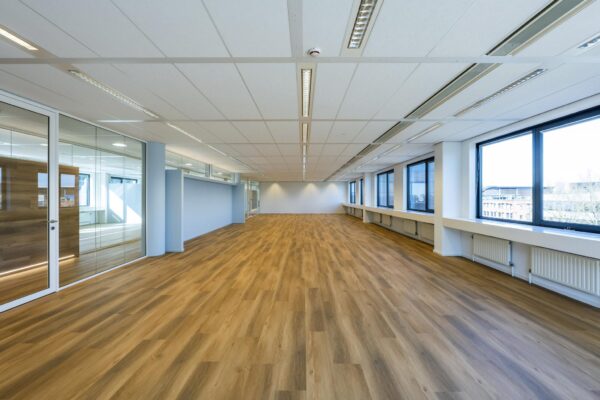 Lichte, leegstaande kantoorruimte aan de Prof. W.H. Keesomlaan met houten vloer, grote ramen en glazen wanden.