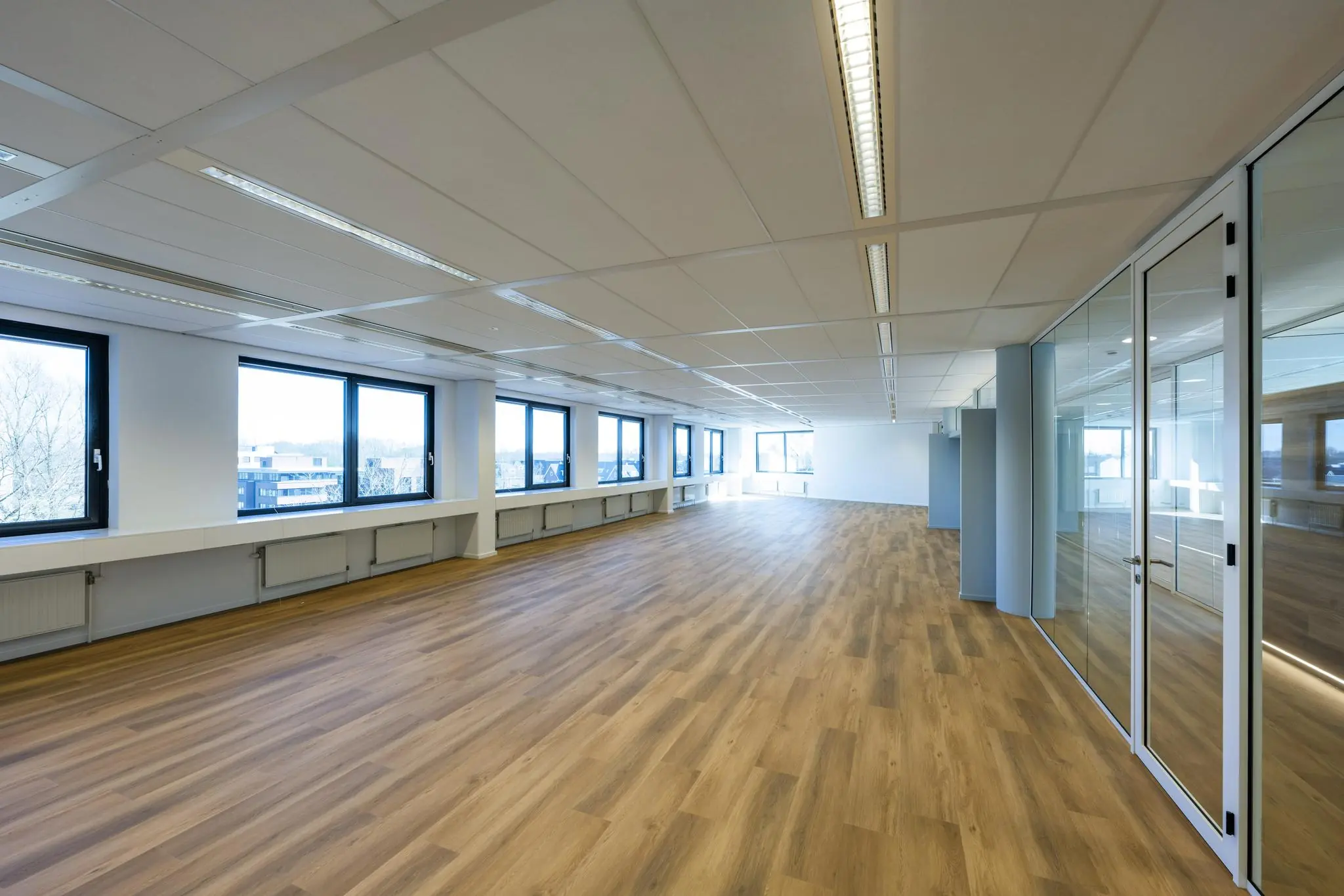 Licht en modern kantoorpand aan de Prof. W.H. Keesomlaan met houten vloer, glazen wanden en grote ramen.