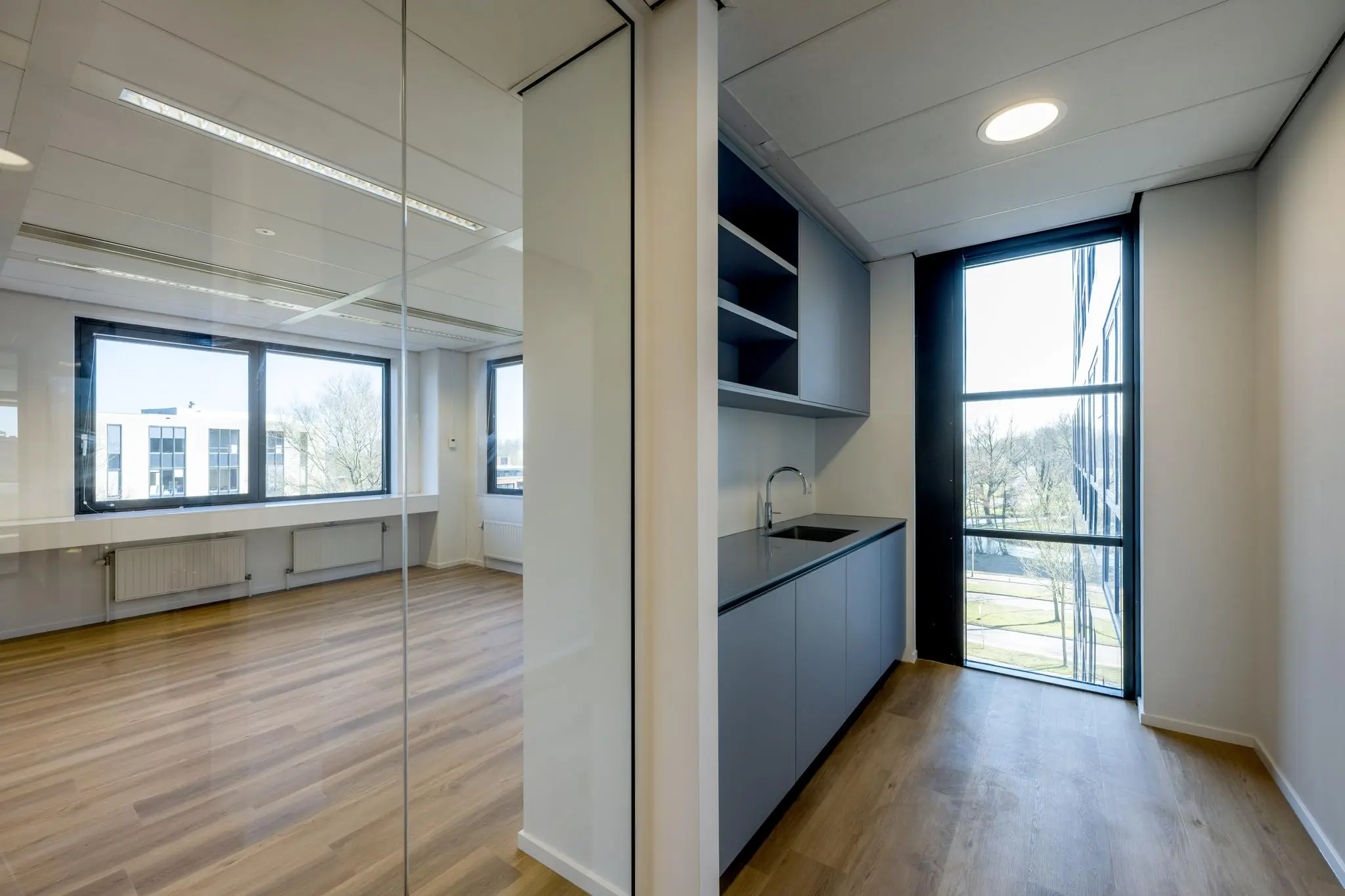Moderne kantoorruimte aan de Prof. W.H. Keesomlaan met houten vloer, grote ramen en een kitchenette.