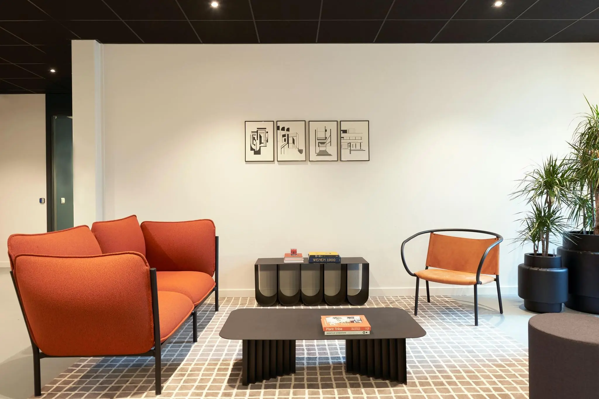 Moderne wachtruimte met oranje bank, designstoel, zwarte salontafel en abstracte kunst aan de muur.