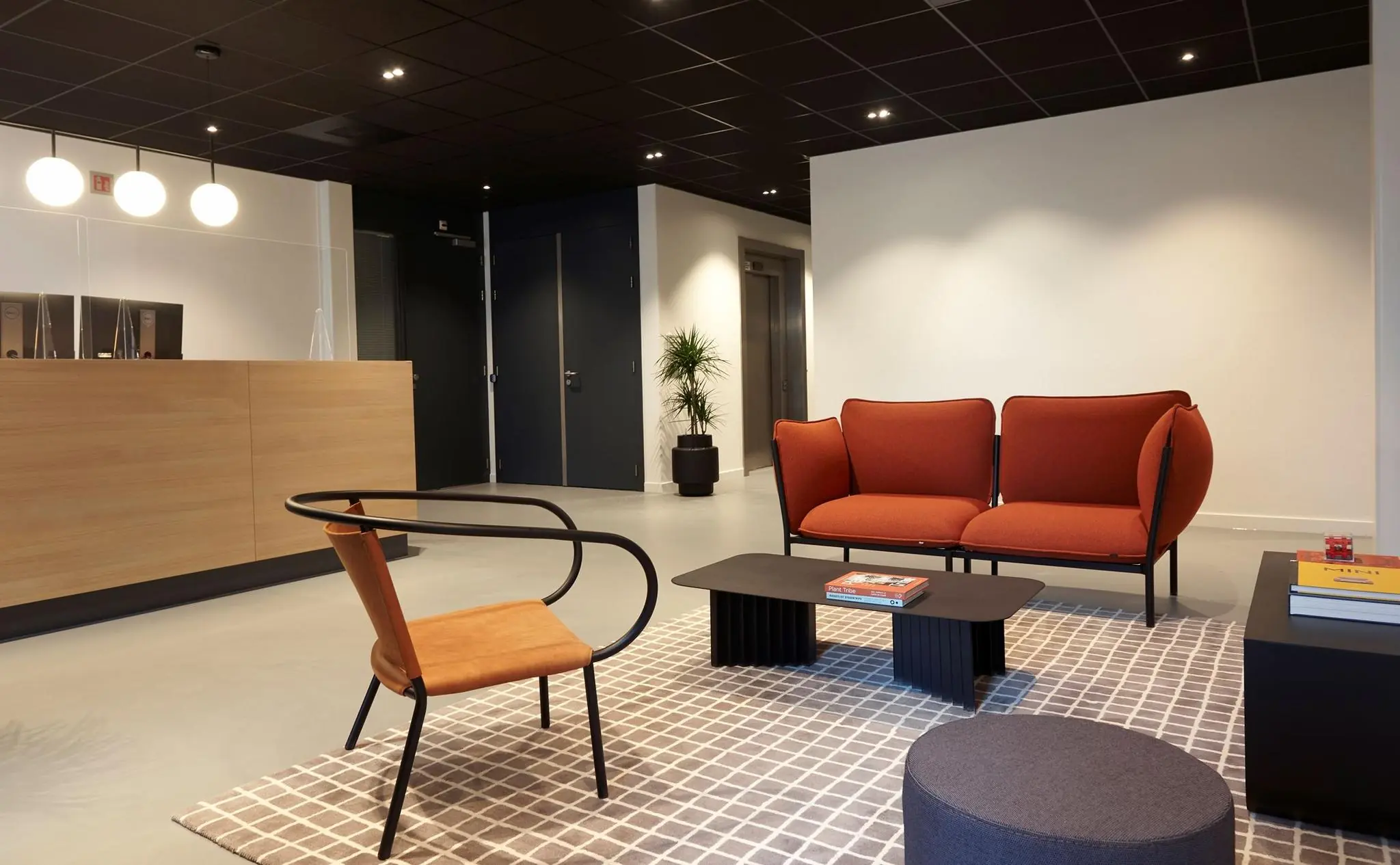 Moderne wachtruimte met een houten balie, designmeubilair in warme tinten en een gestreept vloerkleed.