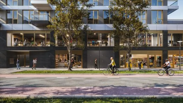Moderne gevel aan de H.J.E. Wenckebachweg met winkels, sportschool, kantoorruimtes en mensen op de stoep en fietspad.