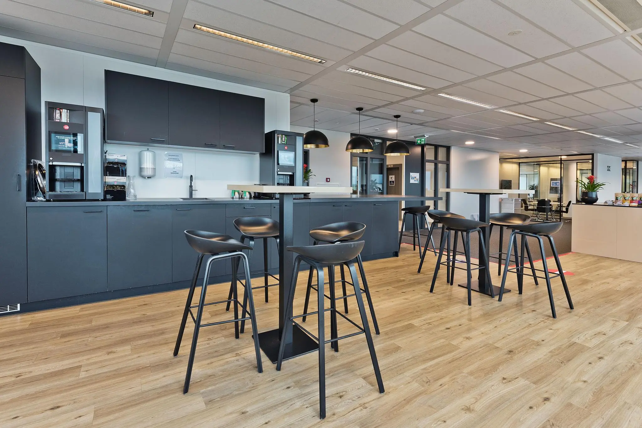 Moderne bedrijfskeuken met hoge tafels, barkrukken en een koffiecorner aan de Prof. W.H. Keesomlaan.