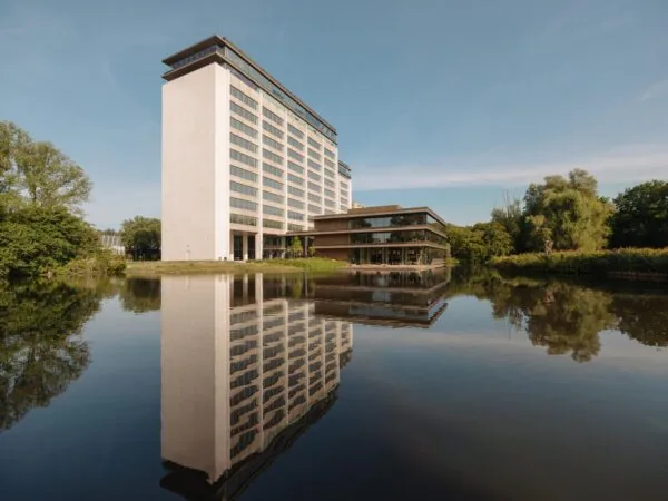 Modern kantoorpand aan de Nachtwachtlaan weerspiegeld in een rustige vijver omgeven door groen.