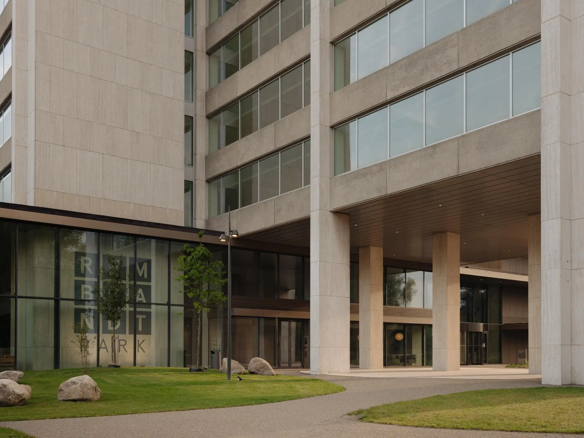 Ingang van een modern kantoorgebouw aan de Nachtwachtlaan met de naam Rembrandt Park zichtbaar op de gevel.