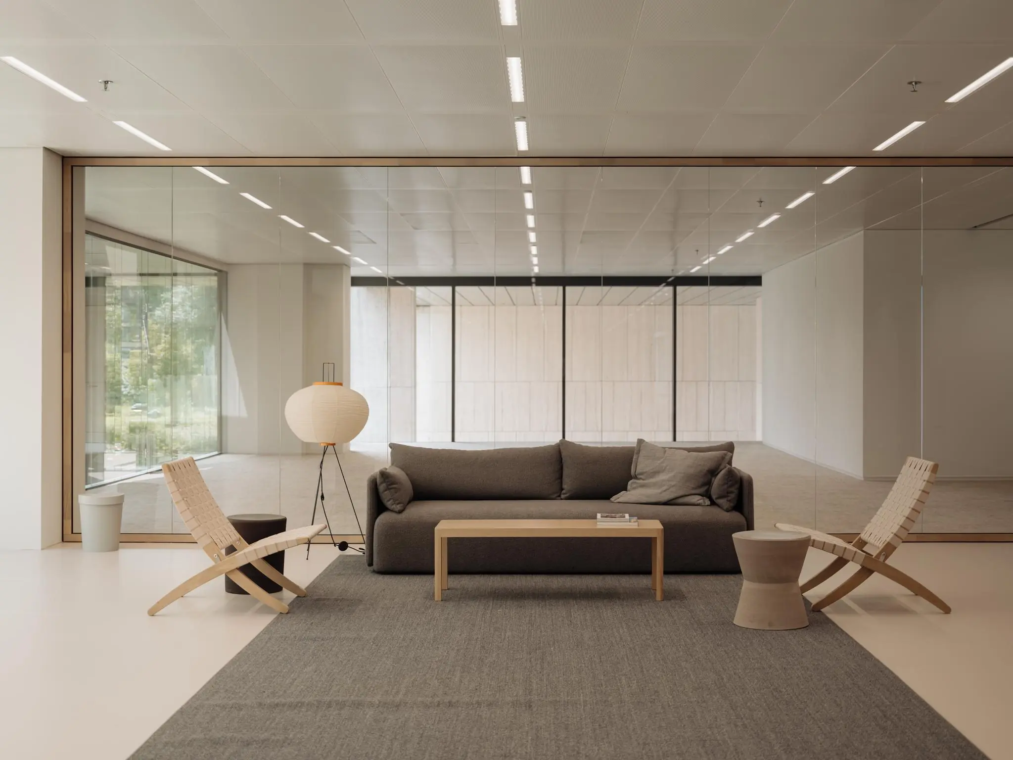 Moderne wachtruimte aan de Nachtwachtlaan met een grijze bank, houten stoelen en glazen wanden.